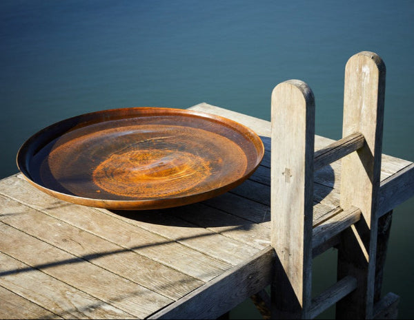 Corten Steel Water Bowl with water by lake