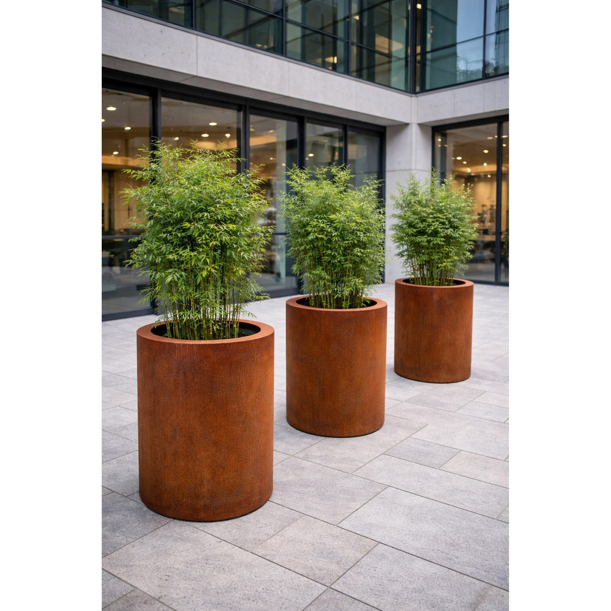 Corten steel cylindrical planters outside modern office building with bamboo, commercial landscape design UK