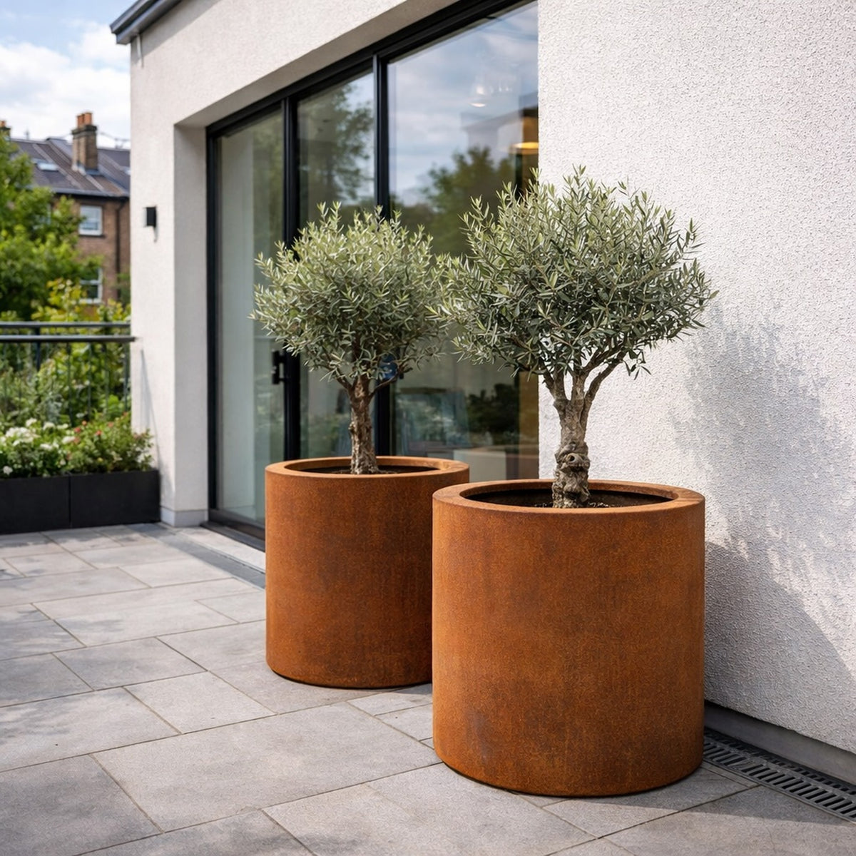 Corten steel cylindrical planters with olive trees on London terrace for contemporary homes