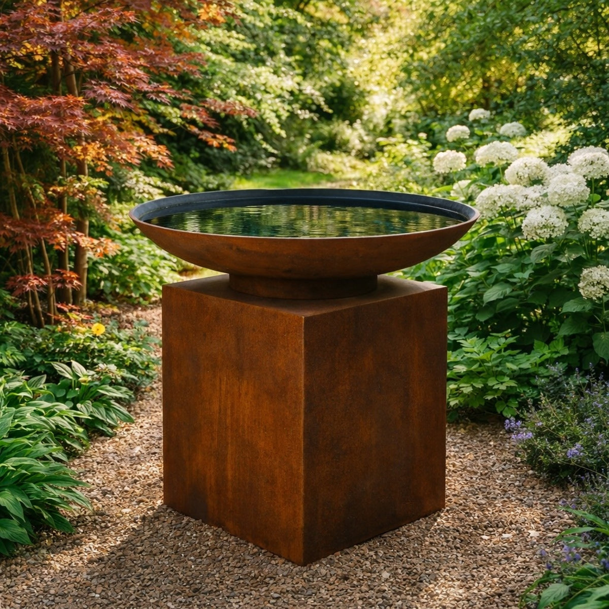 Corten steel water bowl with lined interior on pedestal in a tranquil garden, sculptural garden water feature with rust finish