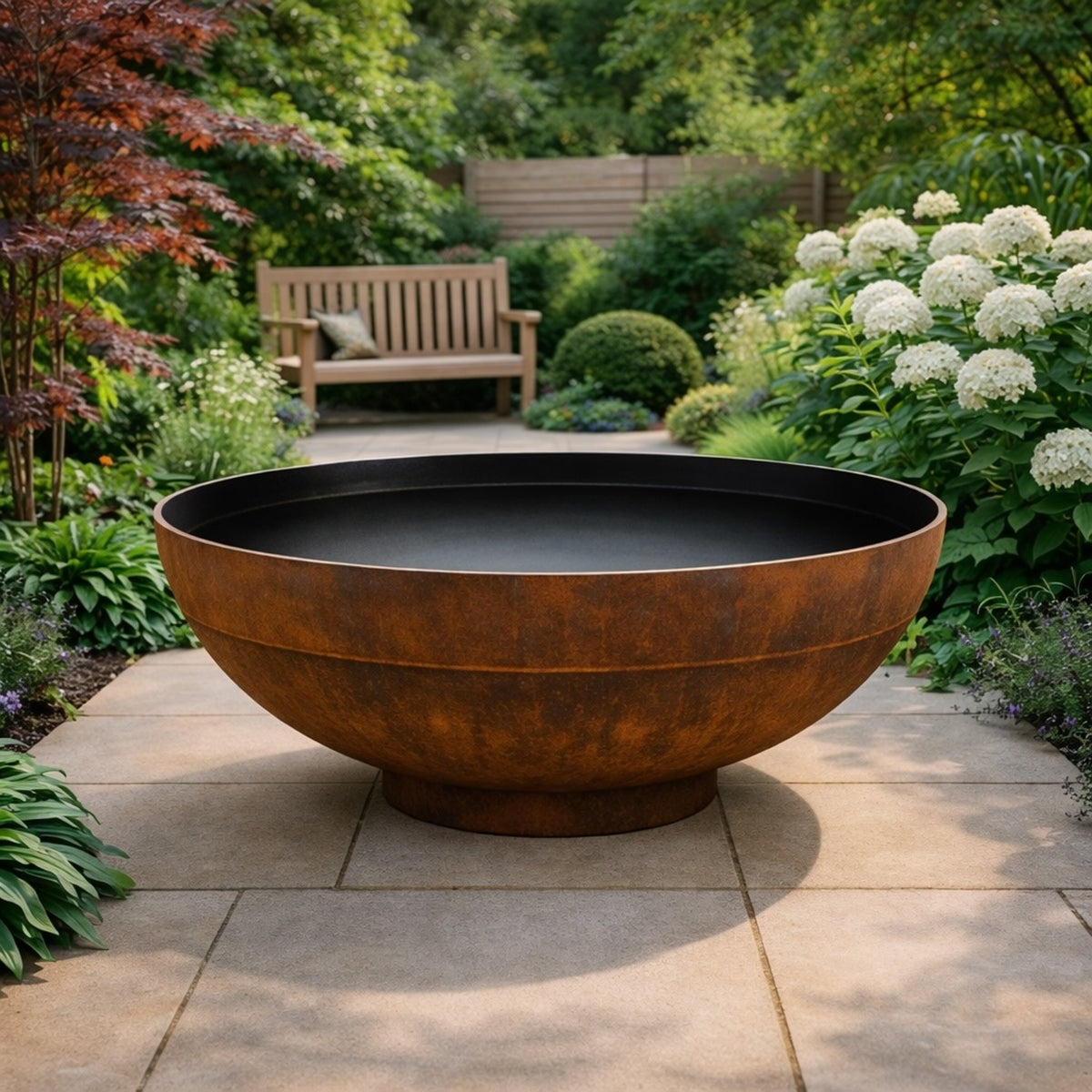 Contemporary corten steel lined water bowl in a landscaped garden with hydrangeas, grasses and modern planting