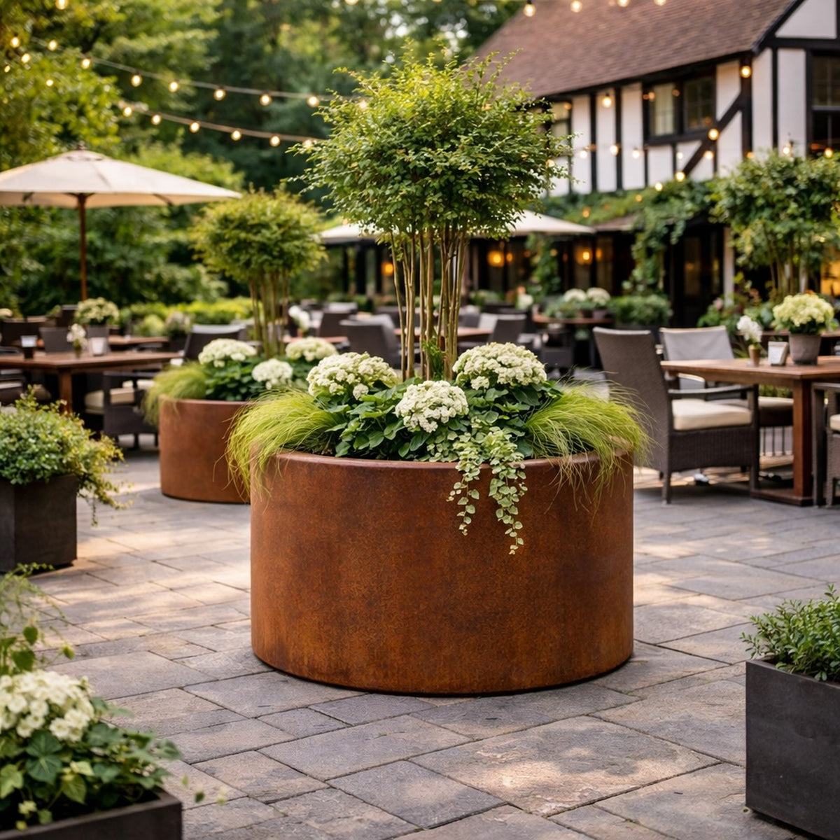 Corten steel cylinder planter in luxury pub garden setting for commercial landscaping UK