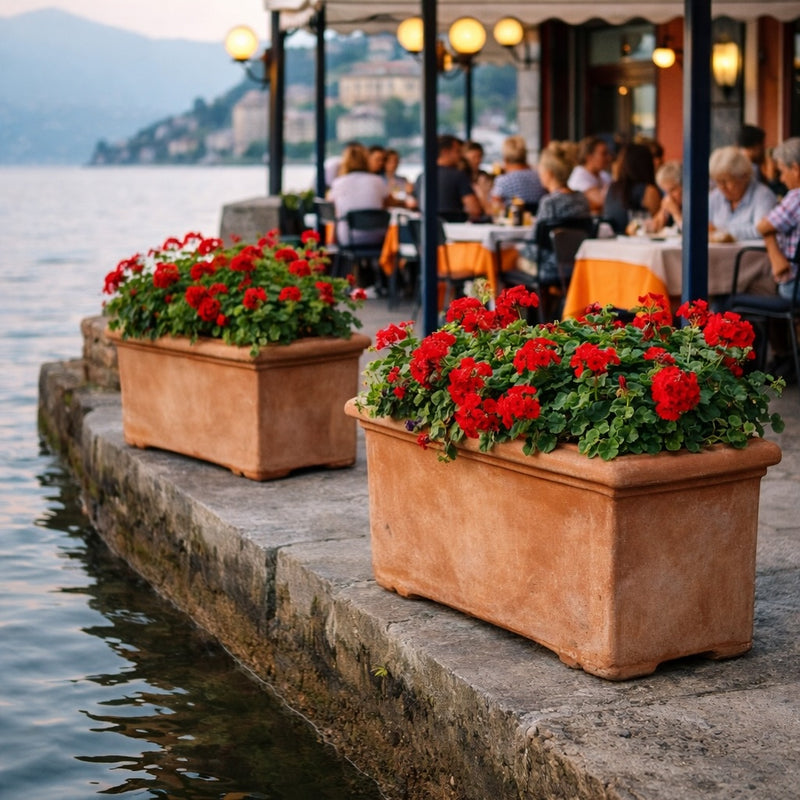 Luxury rectangular terracotta planters with red geraniums beside a Lake Como waterfront café – premium outdoor planters for restaurants and hospitality landscaping