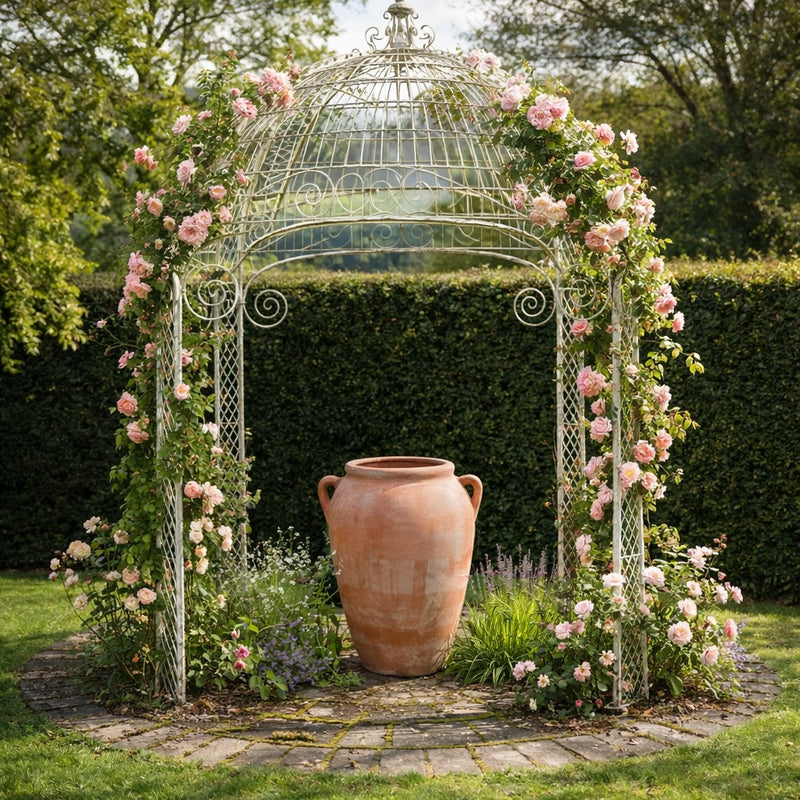 Large terracotta olive jar planter under rose-covered garden pergola in luxury UK garden landscape design